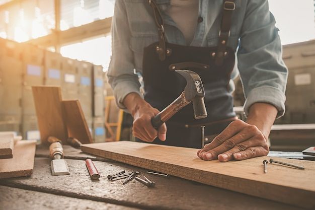 Developments — craftsman hammering nails into wooden product with precision tools in workshop