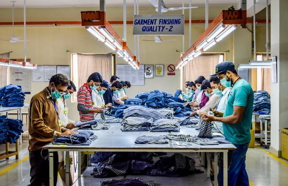 Quality Assurance — Indian factory workers inspecting and checking garment quality on production floor